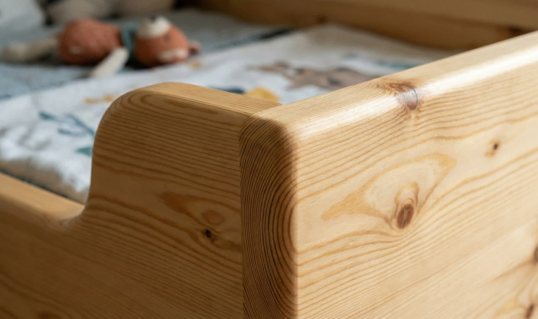 Zbliżenie na grubą ramę łóżka sosnowego z bezpiecznymi, zaokrąglonymi krawędziami i widocznymi naturalnymi słojami